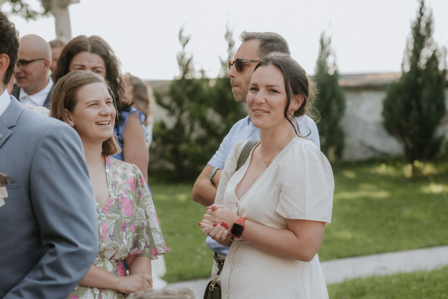 Guests smiling and socializing outdoors at a wedding reception on a sunny day.