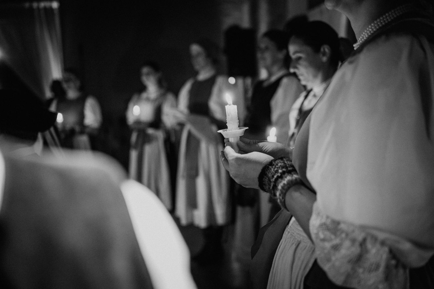 Black and white photo of people holding candles during a religious ceremony or vigil service.