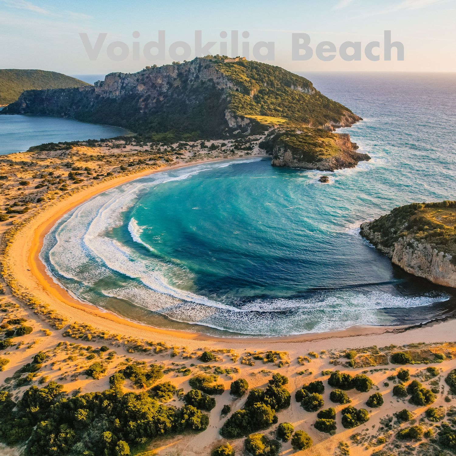Aerial view of Voidokilia Beach, a stunning horseshoe-shaped sandy cove with turquoise waters in Greece.