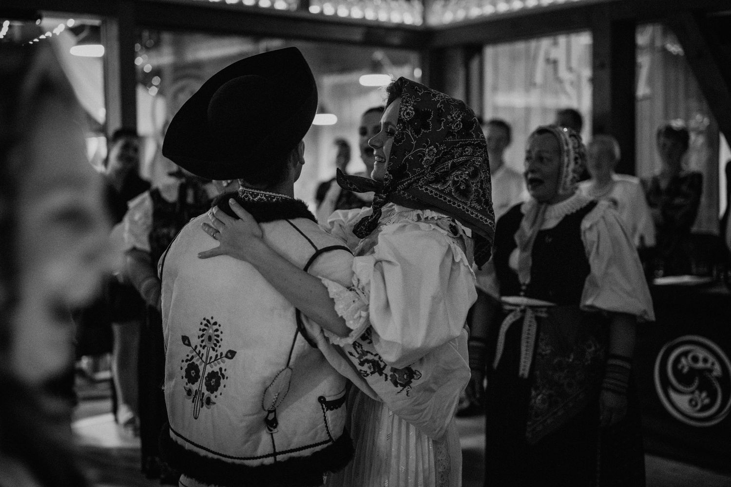 Black and white photo of two people in traditional folk costumes dancing together at a cultural event.