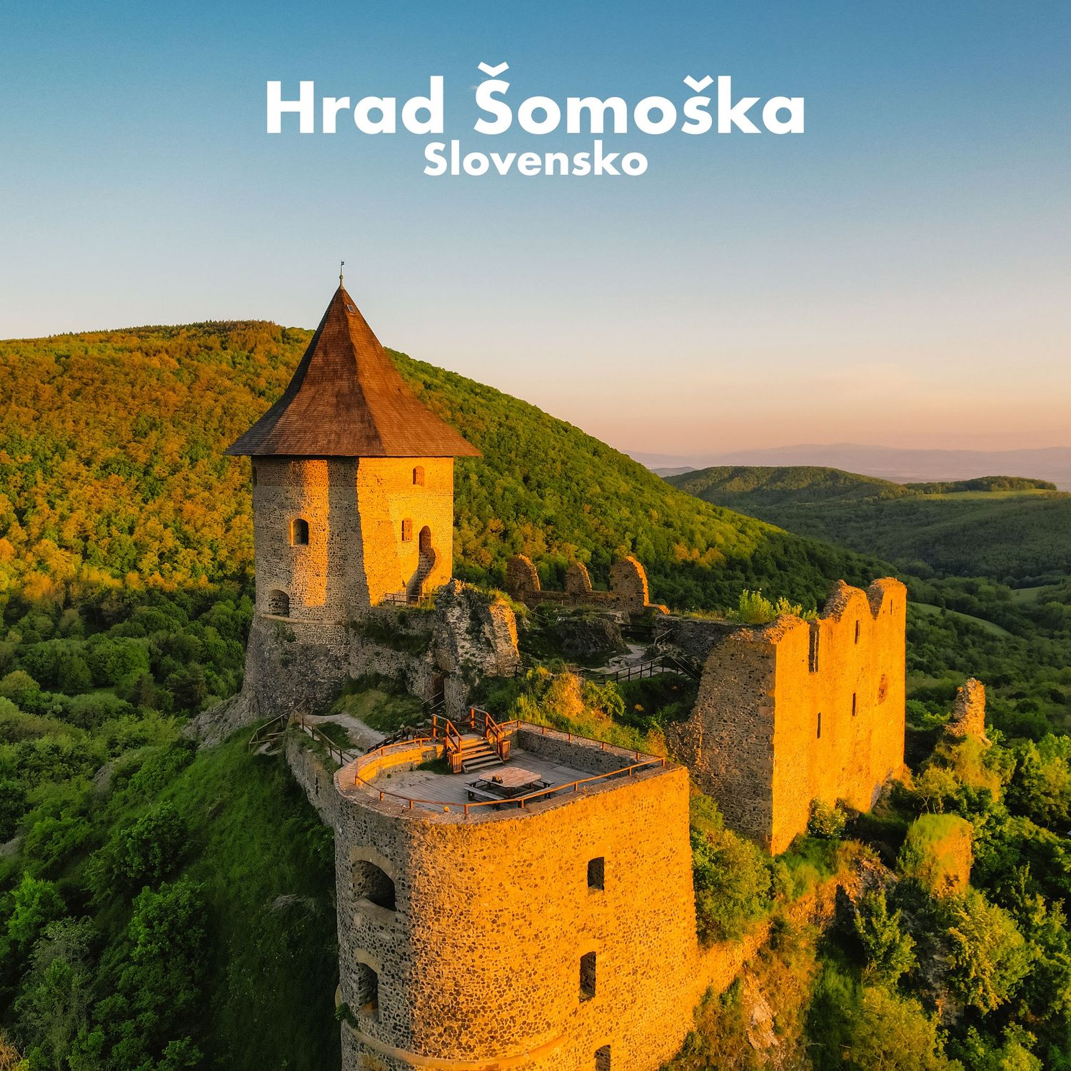 Aerial view of Hrad Somoska castle ruins surrounded by lush green hills at sunset in Slovakia.
