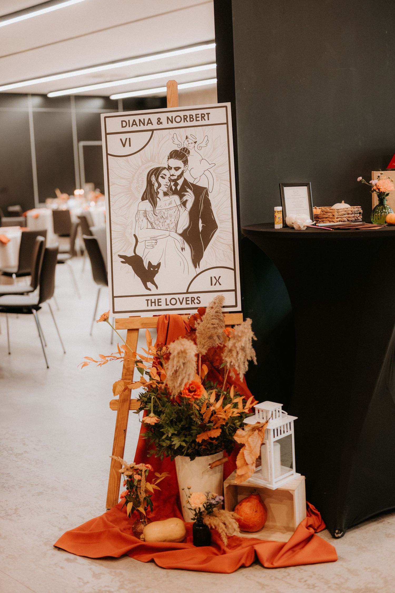 Tarot card wedding welcome sign for Diana & Norbert on easel with autumn floral arrangement and orange fabric.