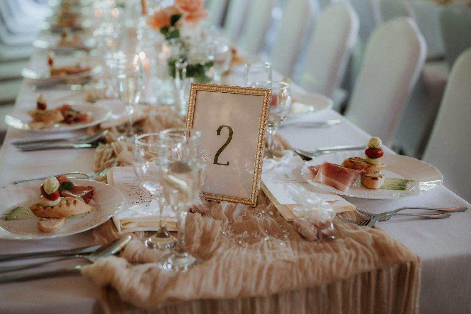 Elegant wedding reception table number 2 with gold frame, champagne runner, fine china, and crystal glasses.