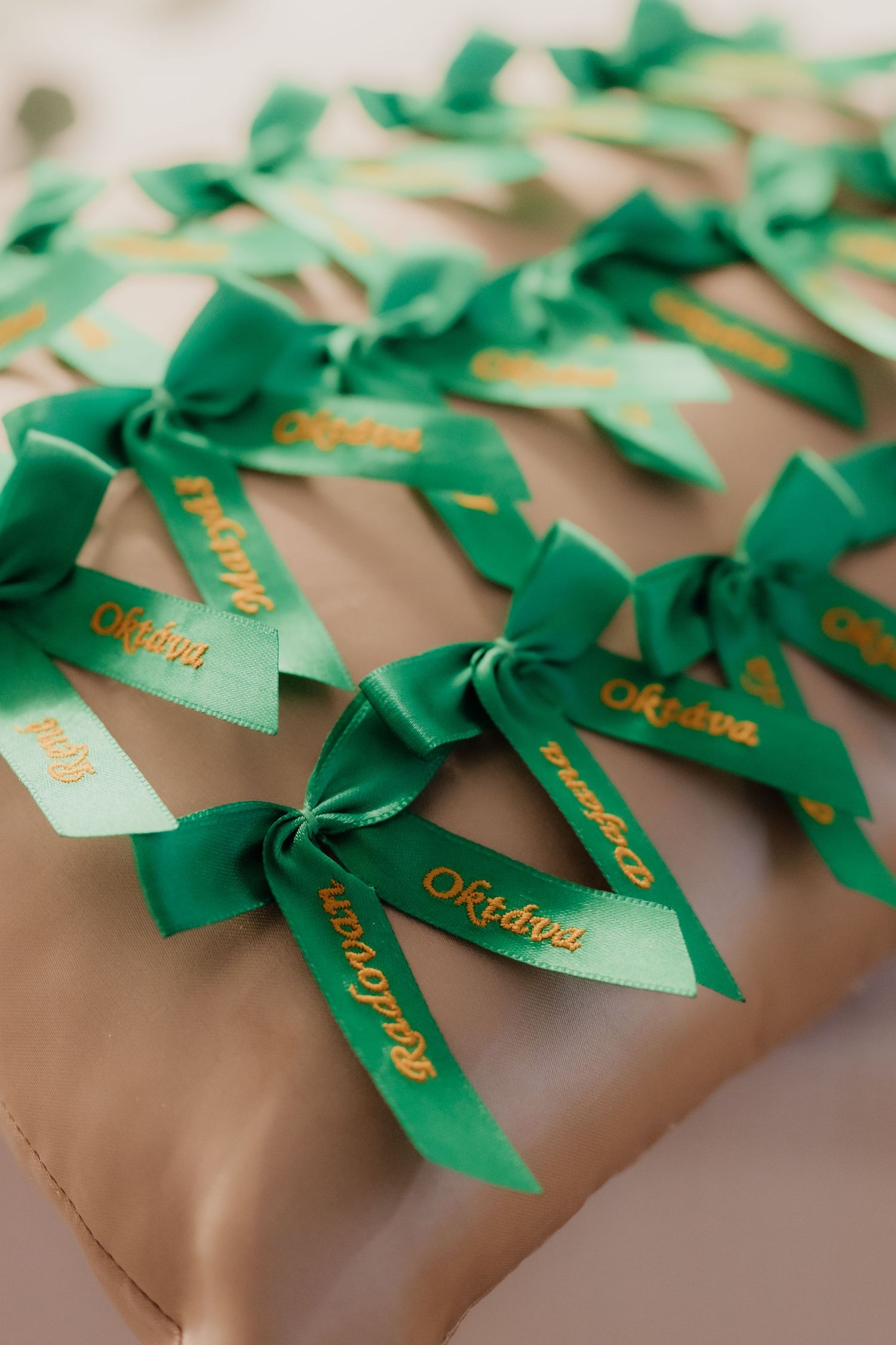 Elegant wrapped gifts with green satin ribbons and gold personalized name tags arranged in rows.