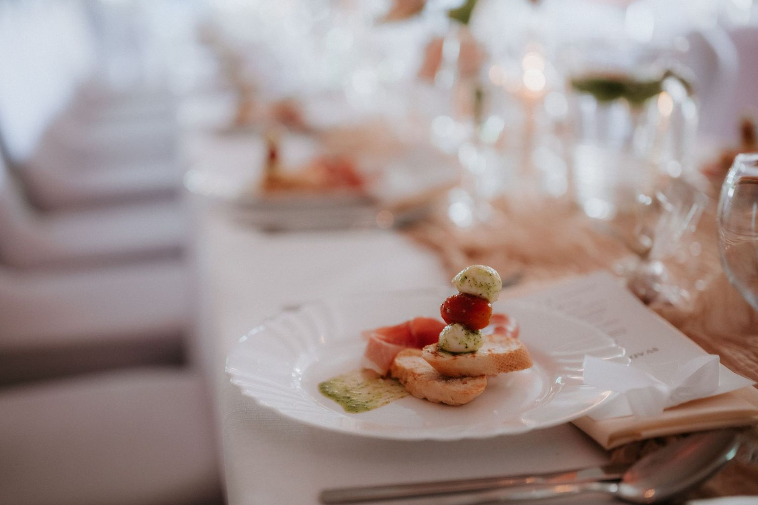 Elegant wedding reception appetizer on white plate with bruschetta, fresh strawberries, and garnish on a formal dining table.