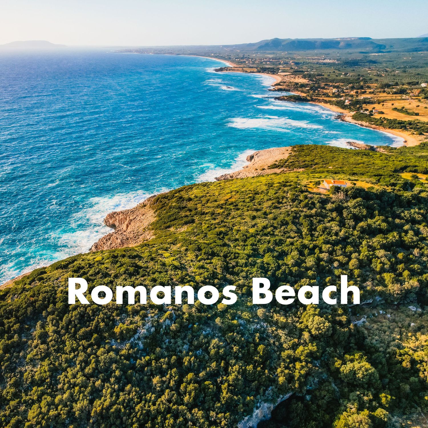 Aerial view of Romanos Beach in Greece, featuring turquoise waters and lush green coastal vegetation.