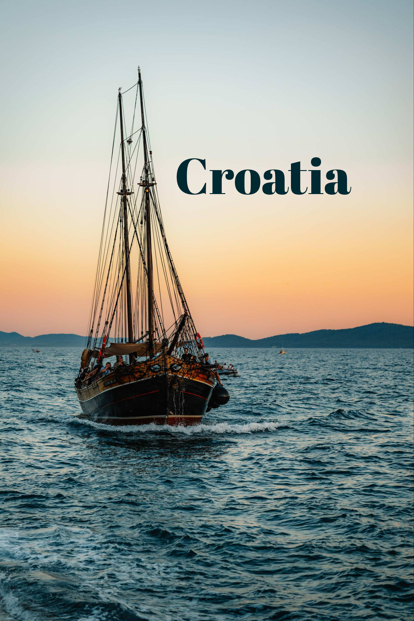 A tall ship sailing on the Adriatic Sea at sunset with mountains in the background in Croatia.