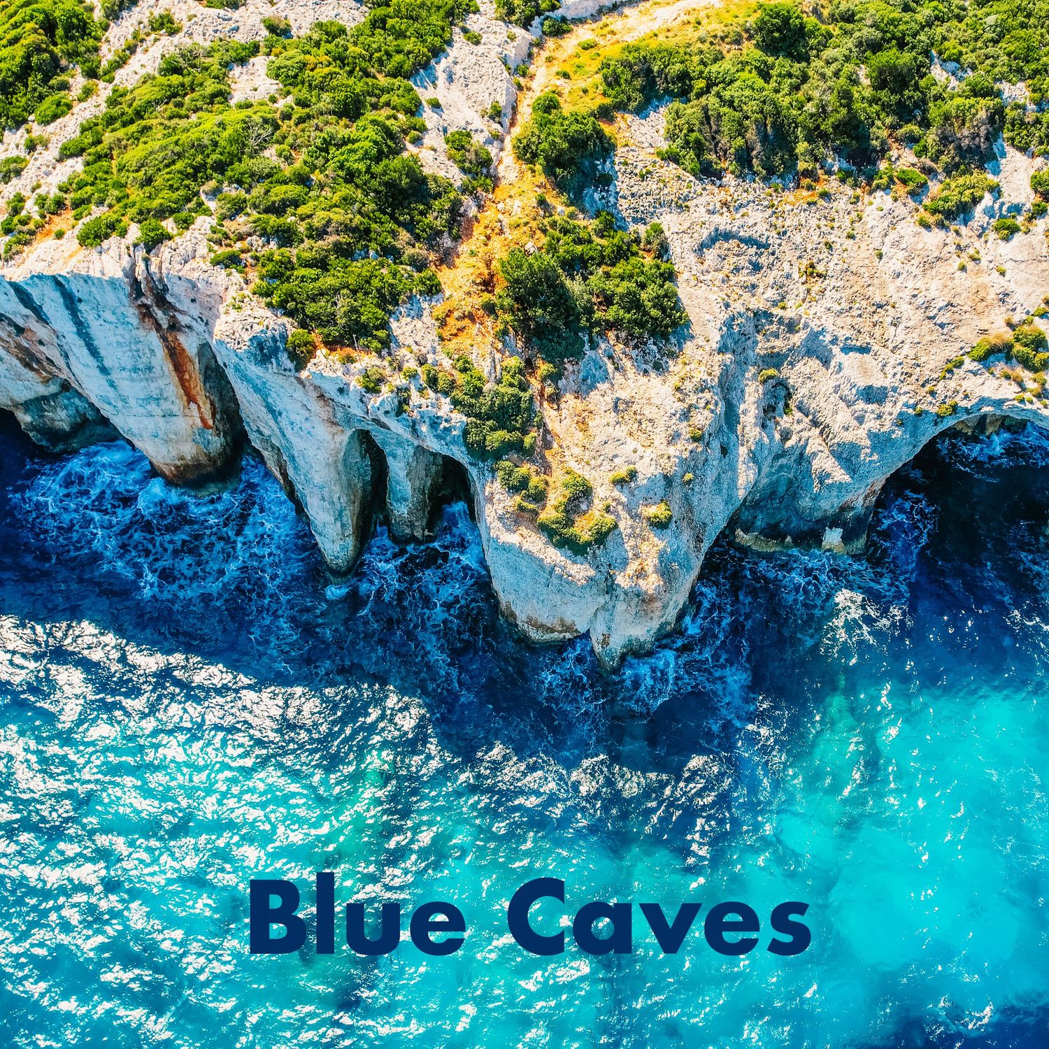Aerial view of the Blue Caves in Greece, featuring striking white limestone cliffs and crystal-clear blue water.