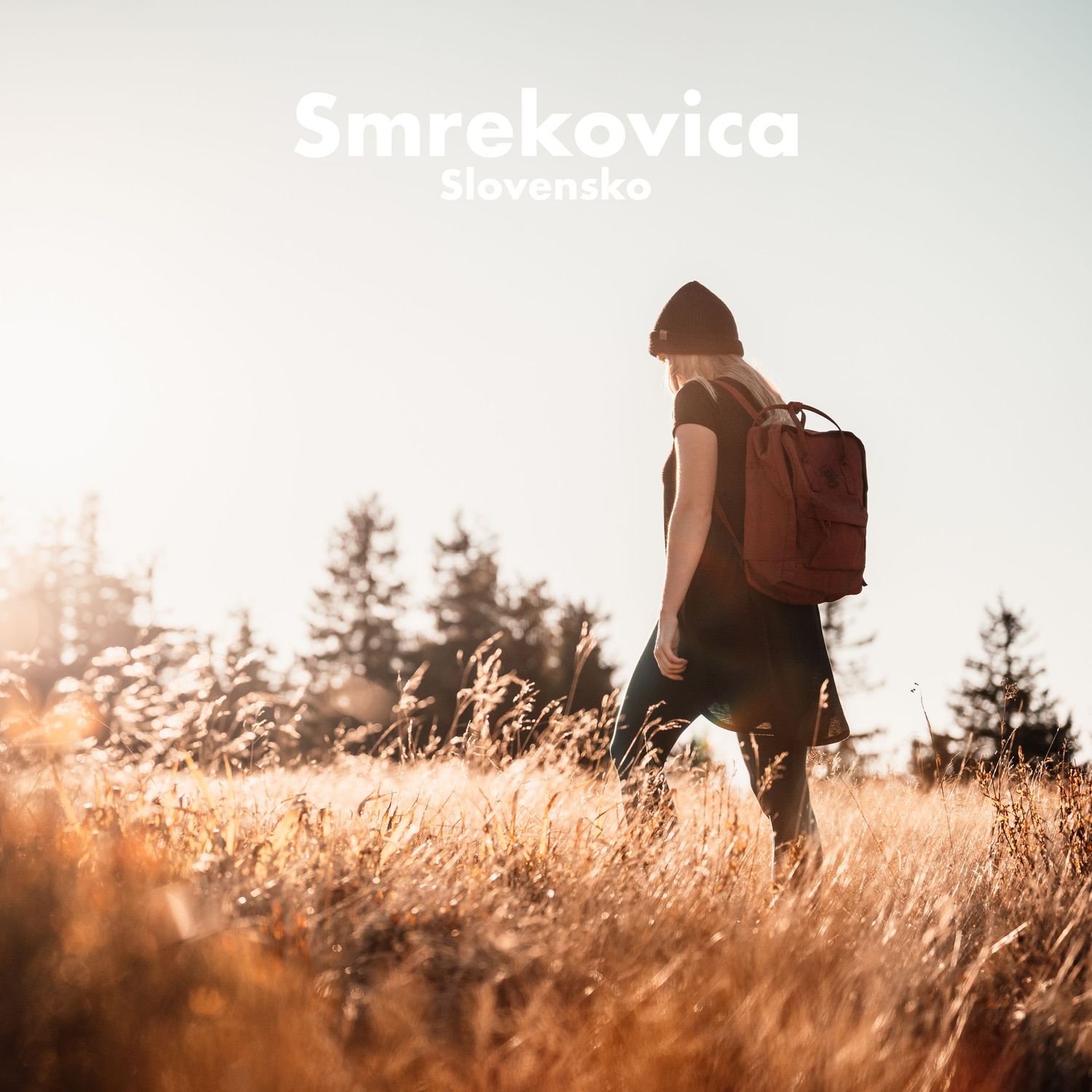 Solo female hiker with red backpack walking through golden meadow at Smrekovica, Slovakia.