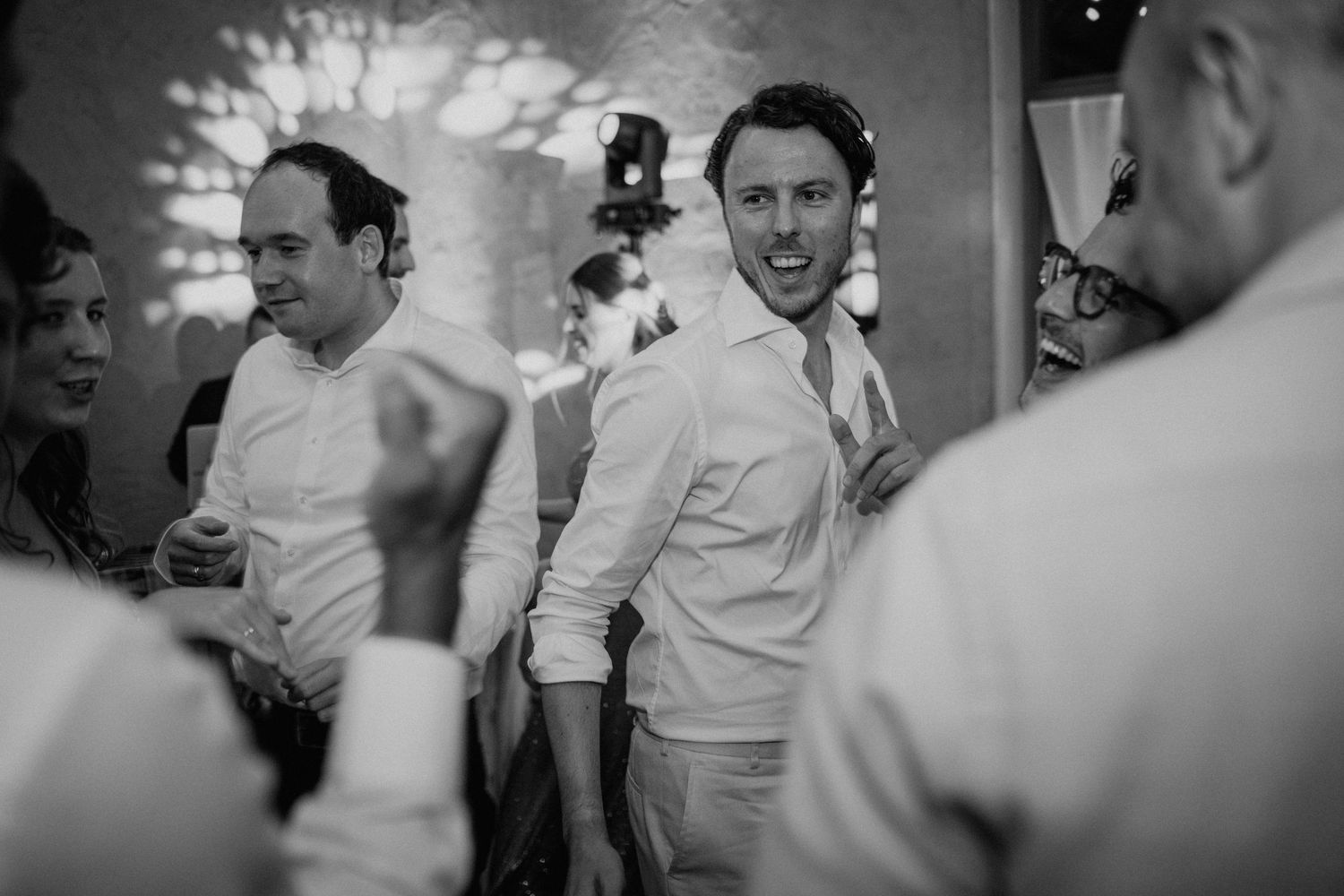 Black and white photo of men laughing and dancing at a wedding reception party.