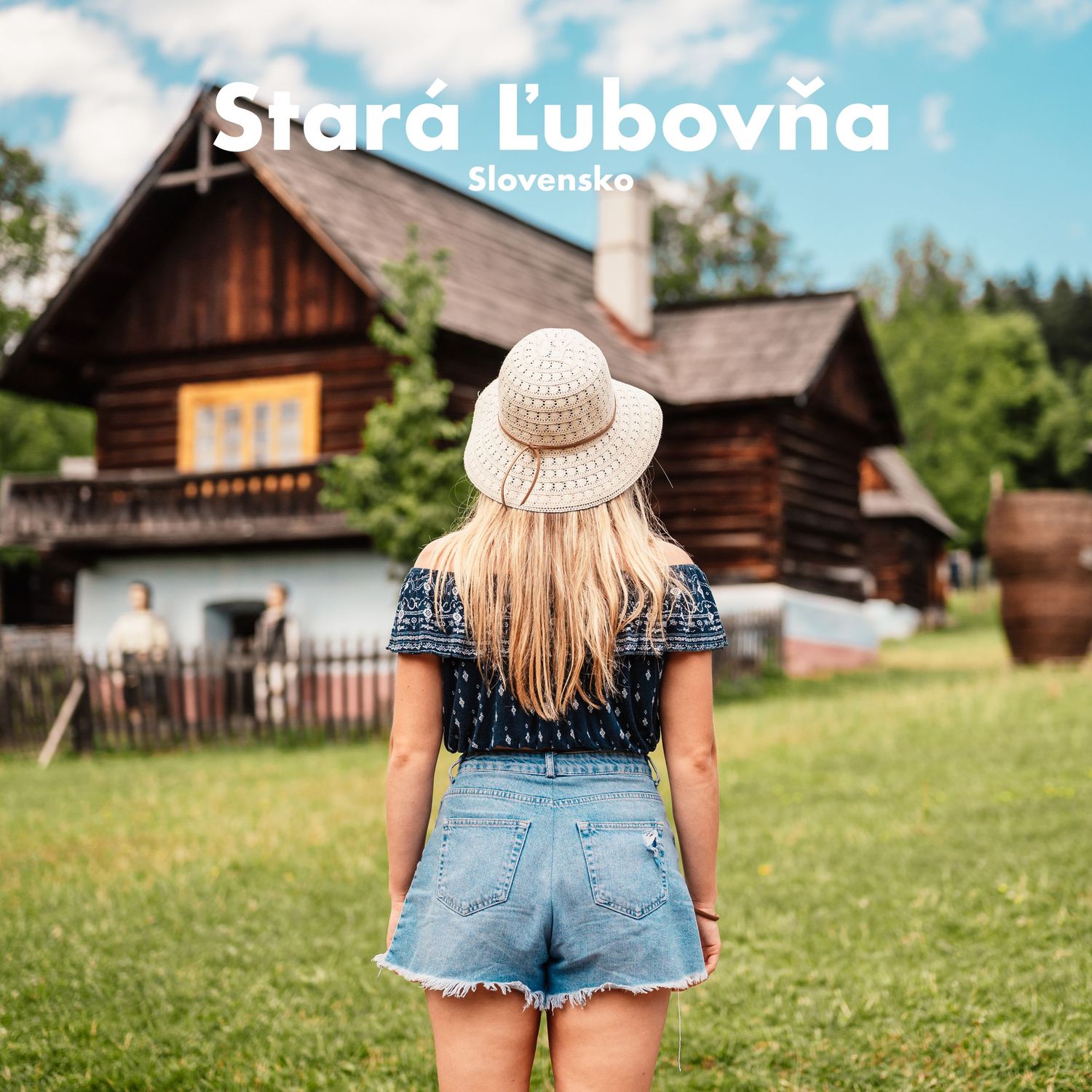 Young woman in shorts admires traditional wooden folk houses at Stara Lubovna open-air museum, Slovakia.