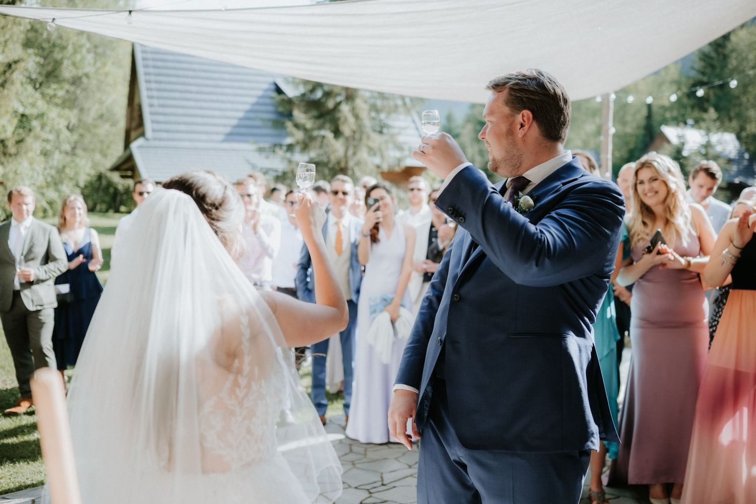 Bride and groom share first dance outdoors at wedding reception with guests celebrating around them.