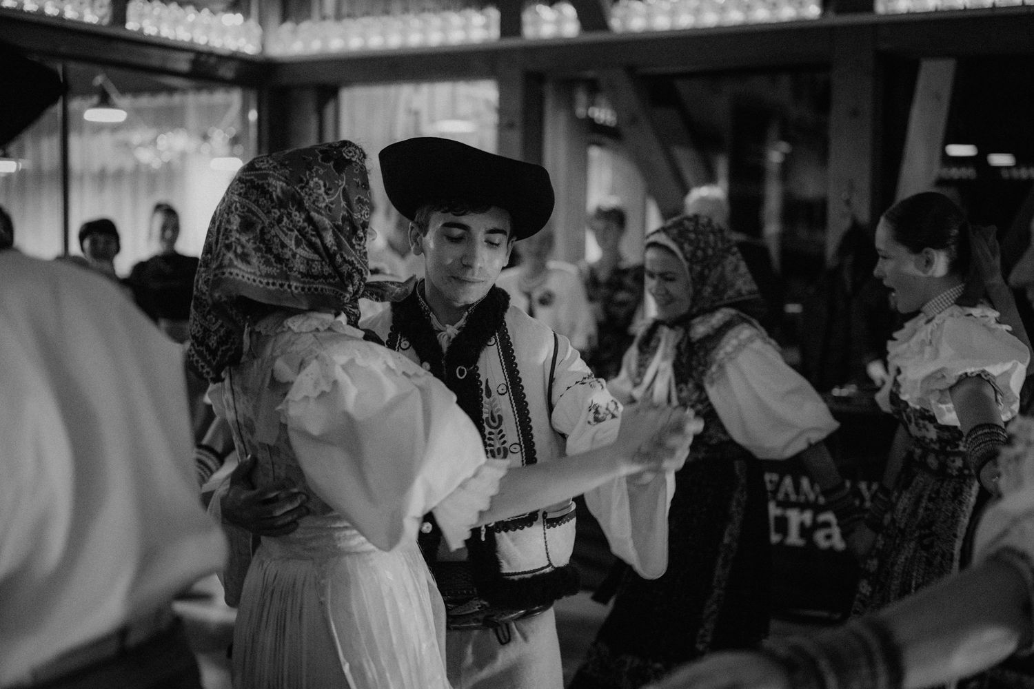 Black and white photo of people in traditional folk costumes dancing at a cultural celebration.