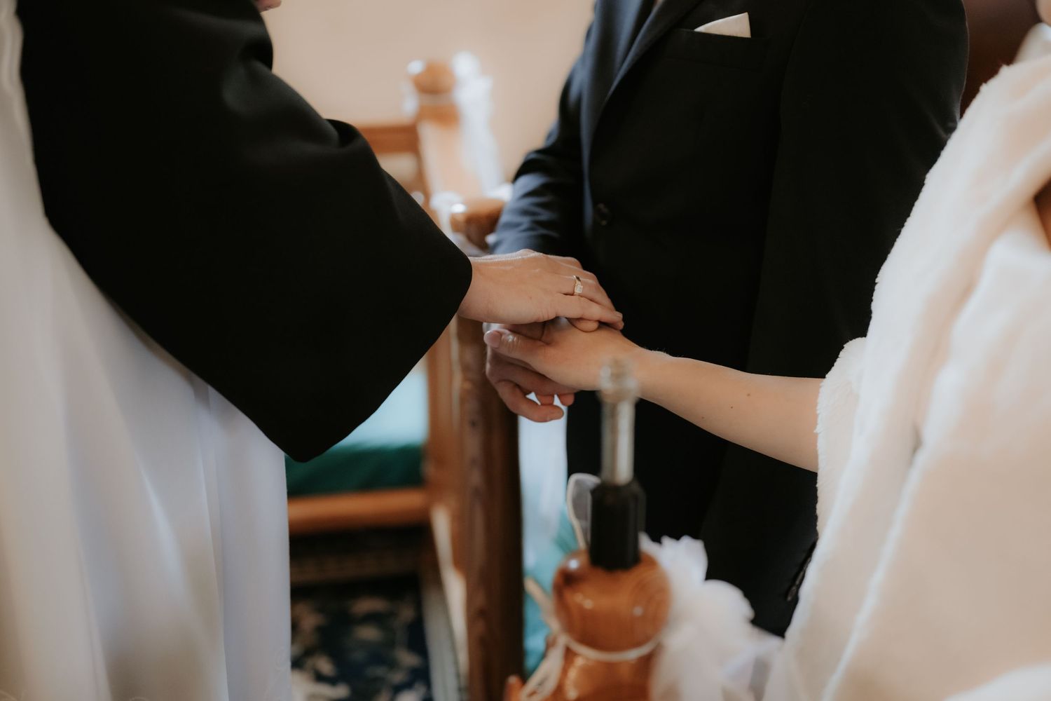 Bride and groom exchanging rings during wedding ceremony at church altar, close-up of hands.