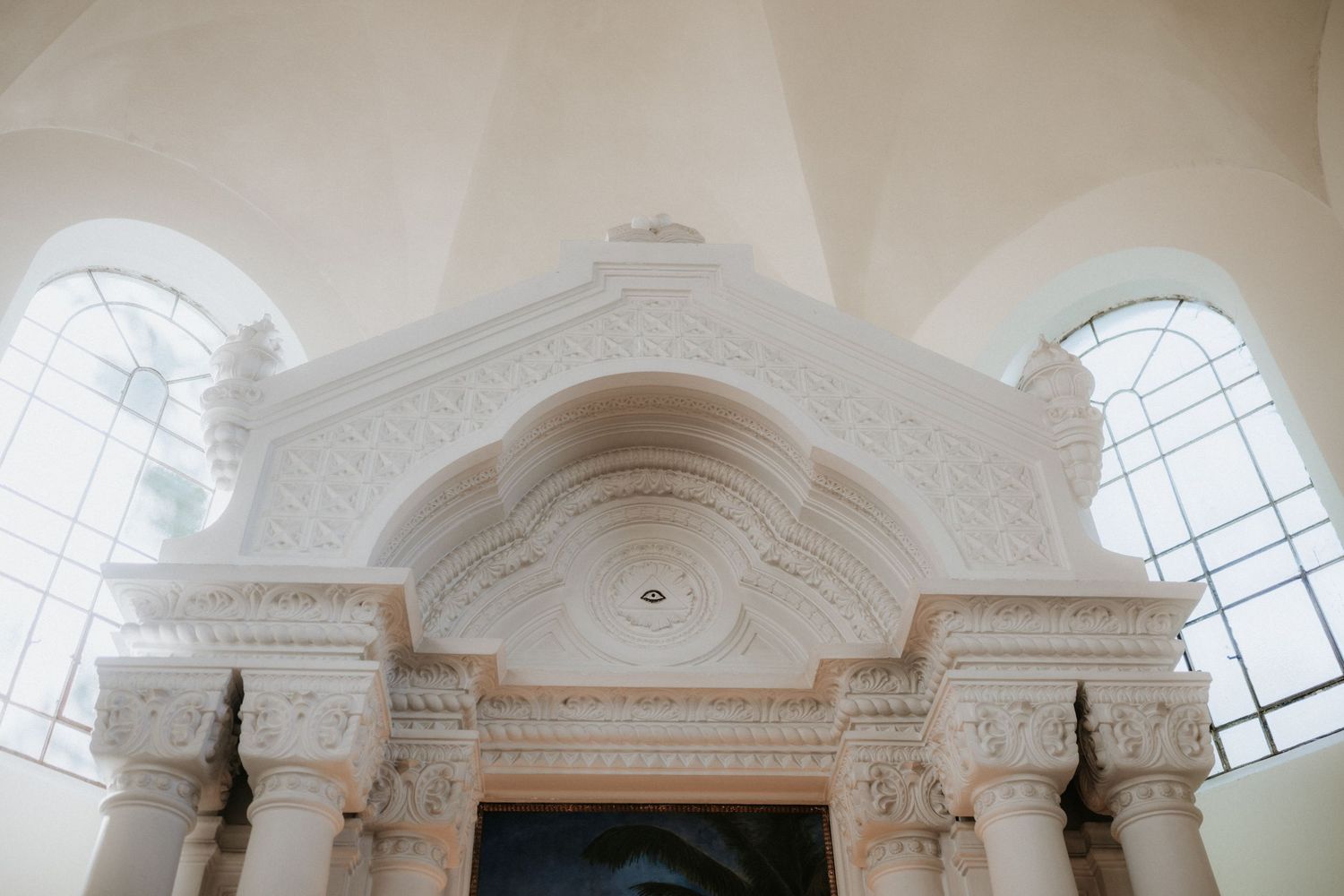Ornate white plaster arch with intricate baroque detailing inside a bright classical church interior.