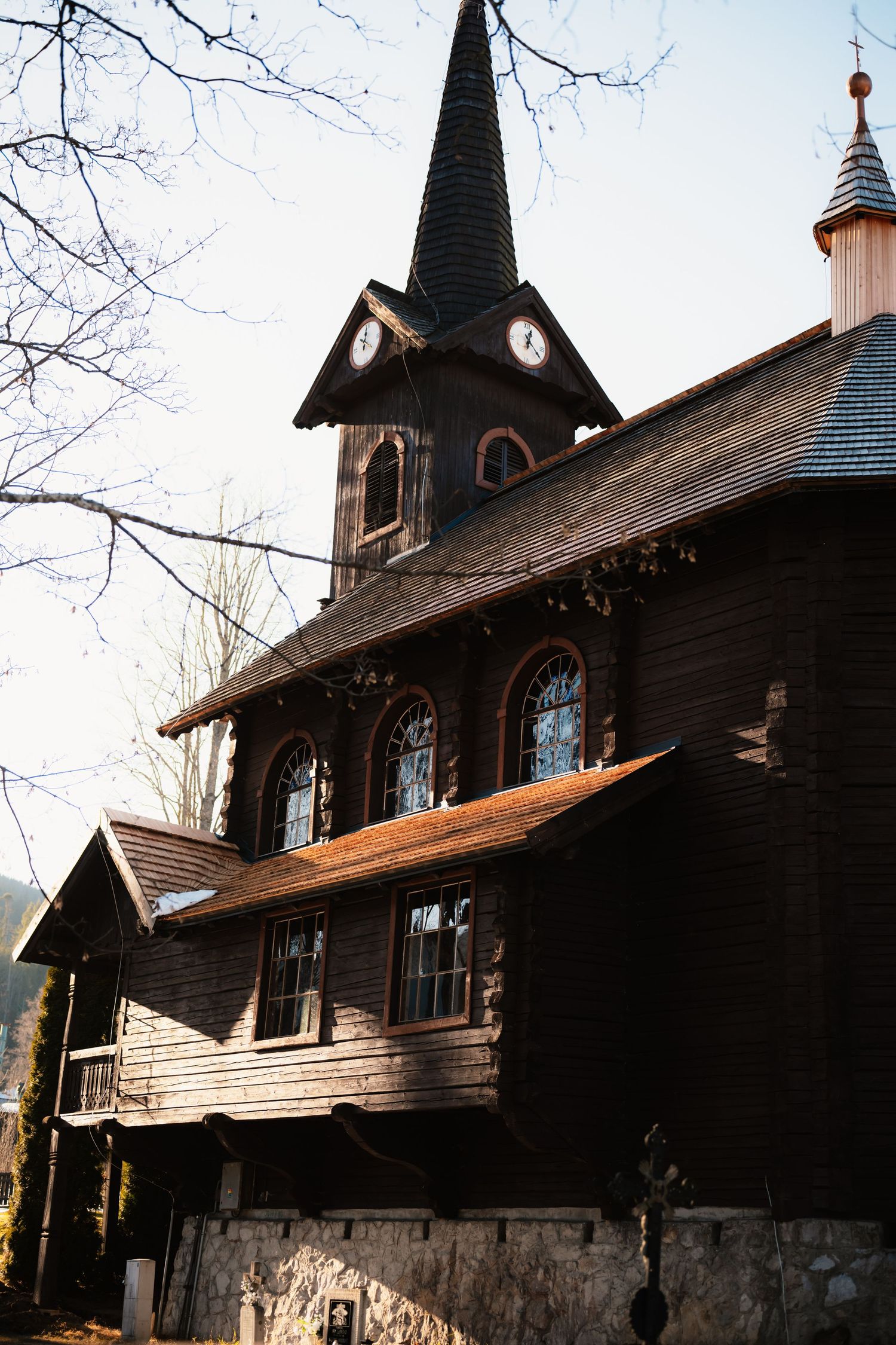Dark wooden historic church with clock tower and steeple against a clear winter sky.