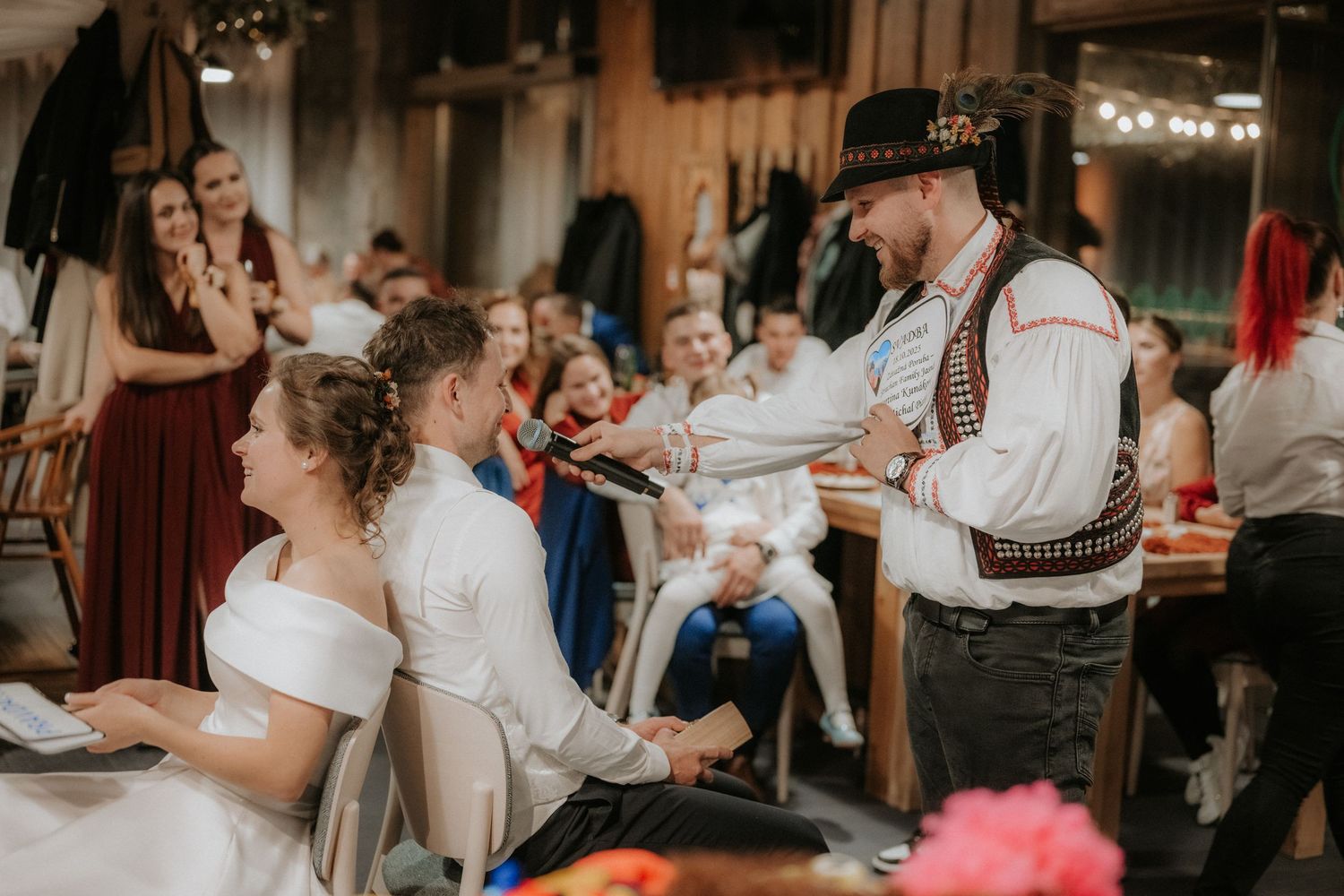 Traditional folk musician performing at a rustic wedding reception for a bride and groom seated at a decorated table.