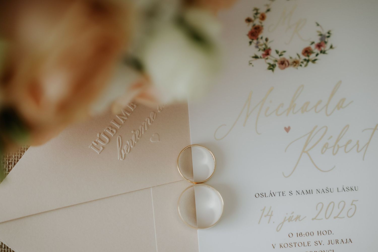 Elegant wedding invitation with gold rings for Michaela and Robert, dated August 14, 2025.