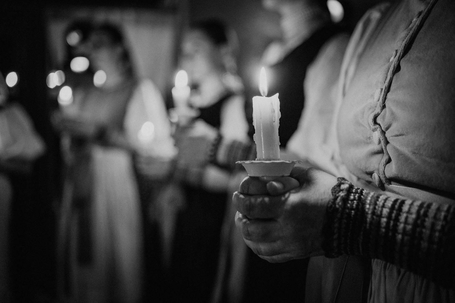 Black and white photo of people holding lit candles during a candlelight ceremony or religious service.