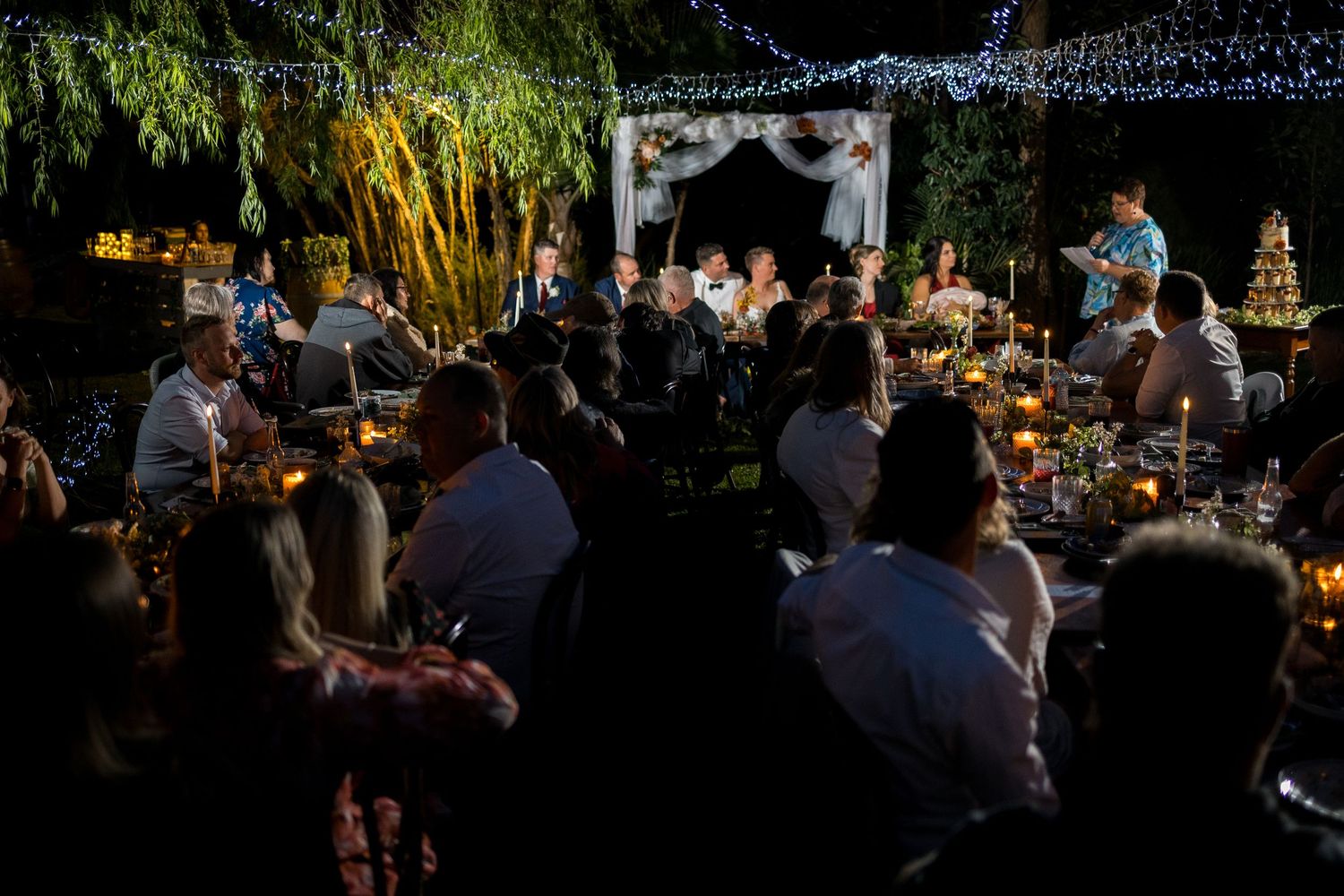 Evening wedding reception with string lights creating a magical outdoor atmosphere.