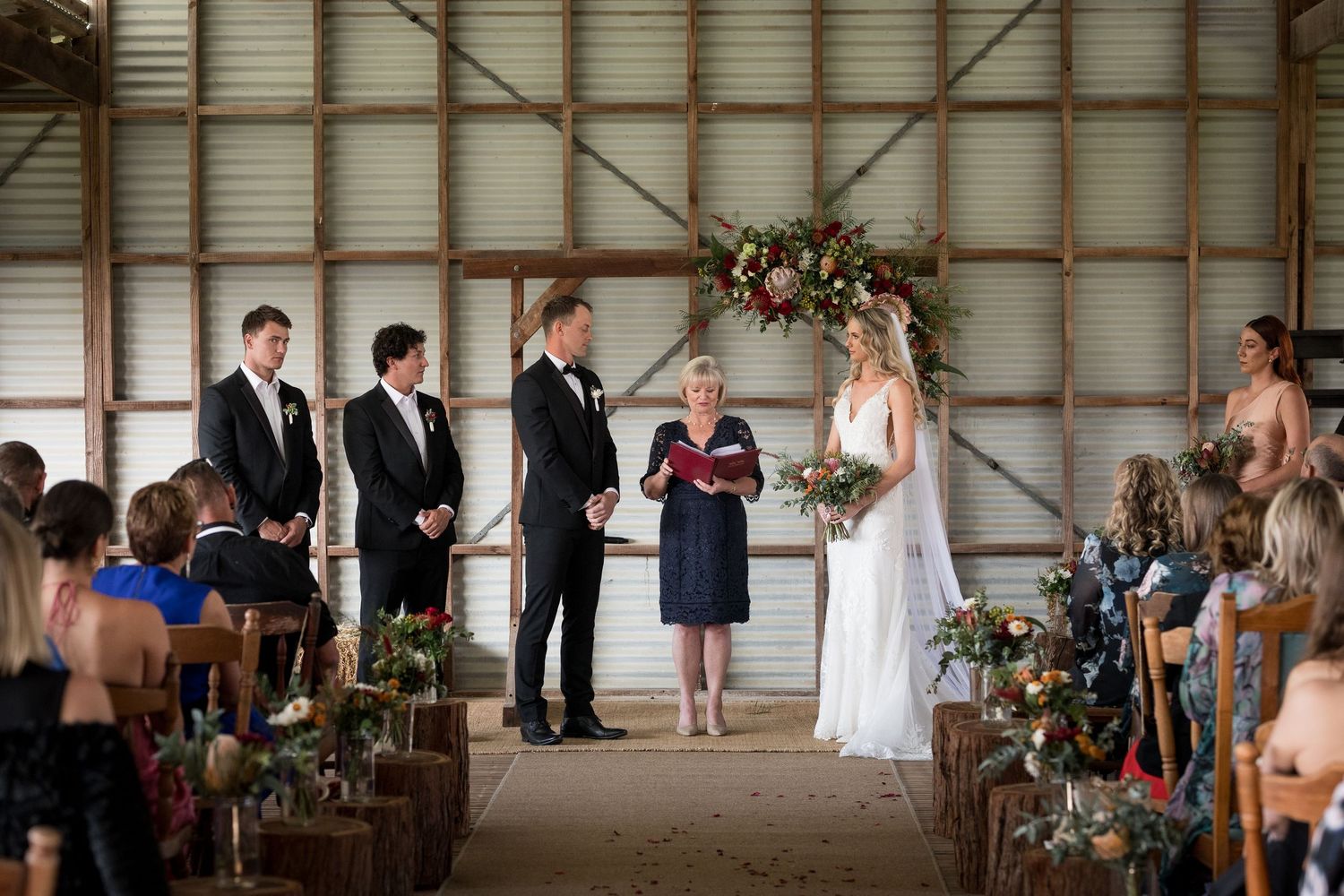 Rustic barn wedding ceremony setup with rows of chairs and floral decorations.