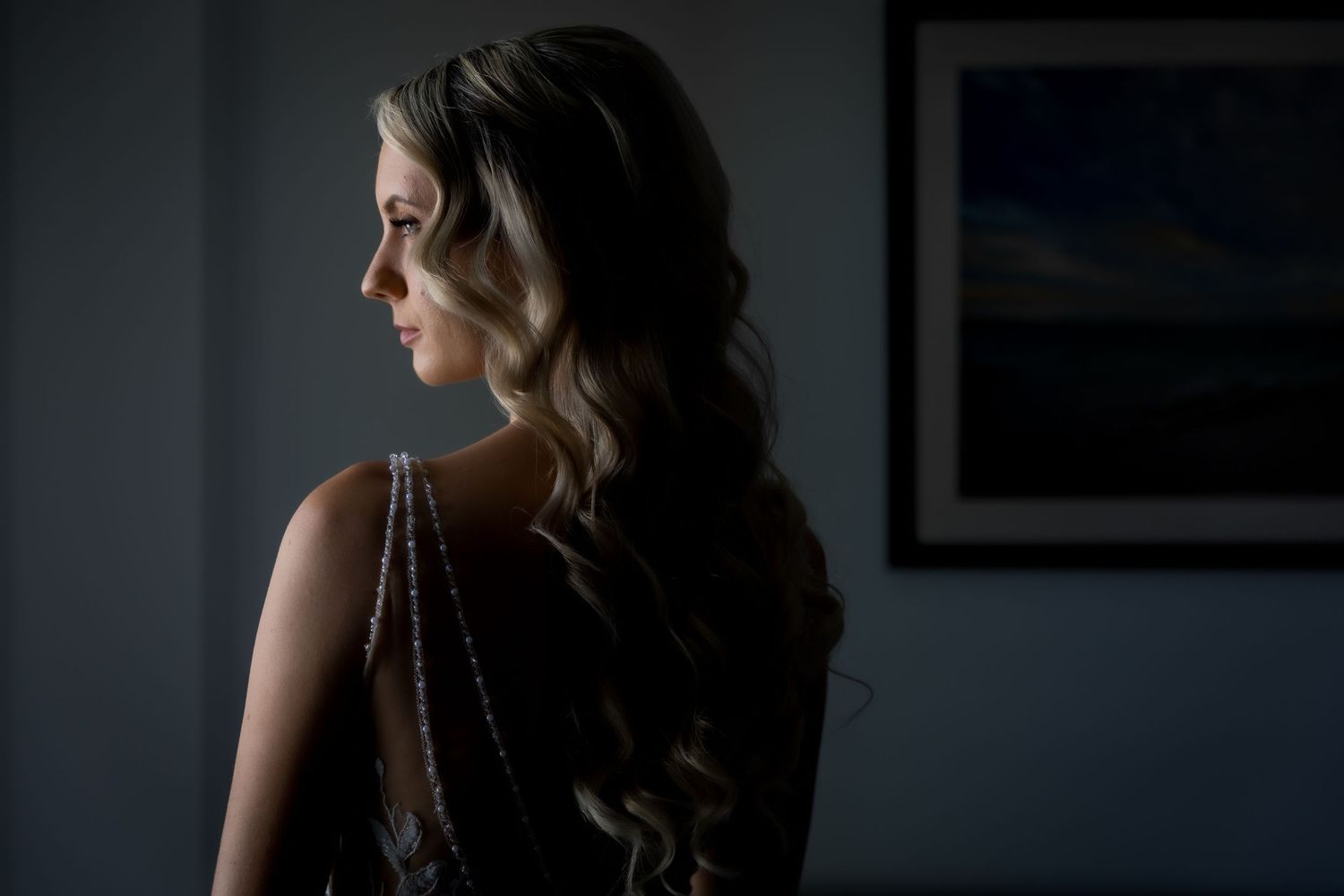 Dramatic side lighting creates a moody portrait in a dark room.