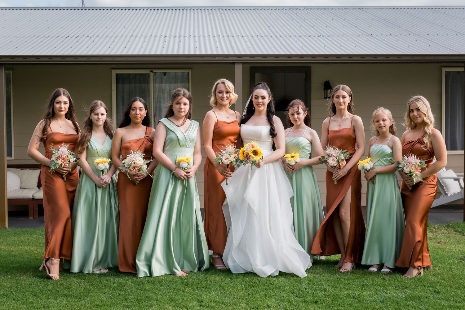 Wedding party in mint green and coral dresses posed on rustic wooden steps.