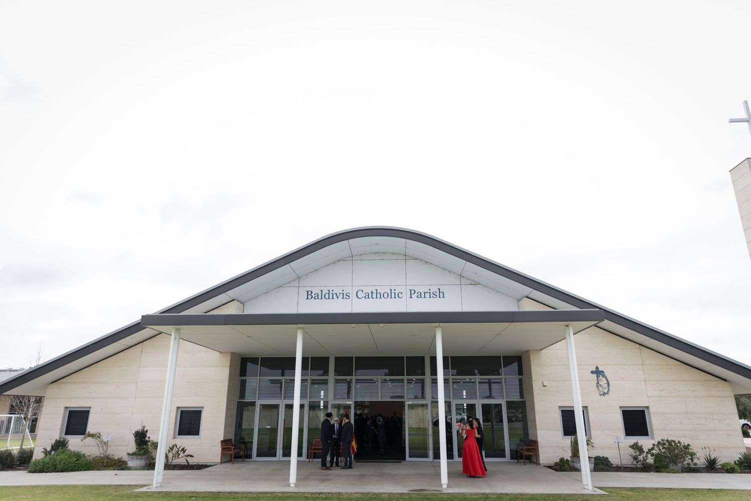 Exterior view of Baldwin Catholic Parish church building with guests arriving for a wedding ceremony.