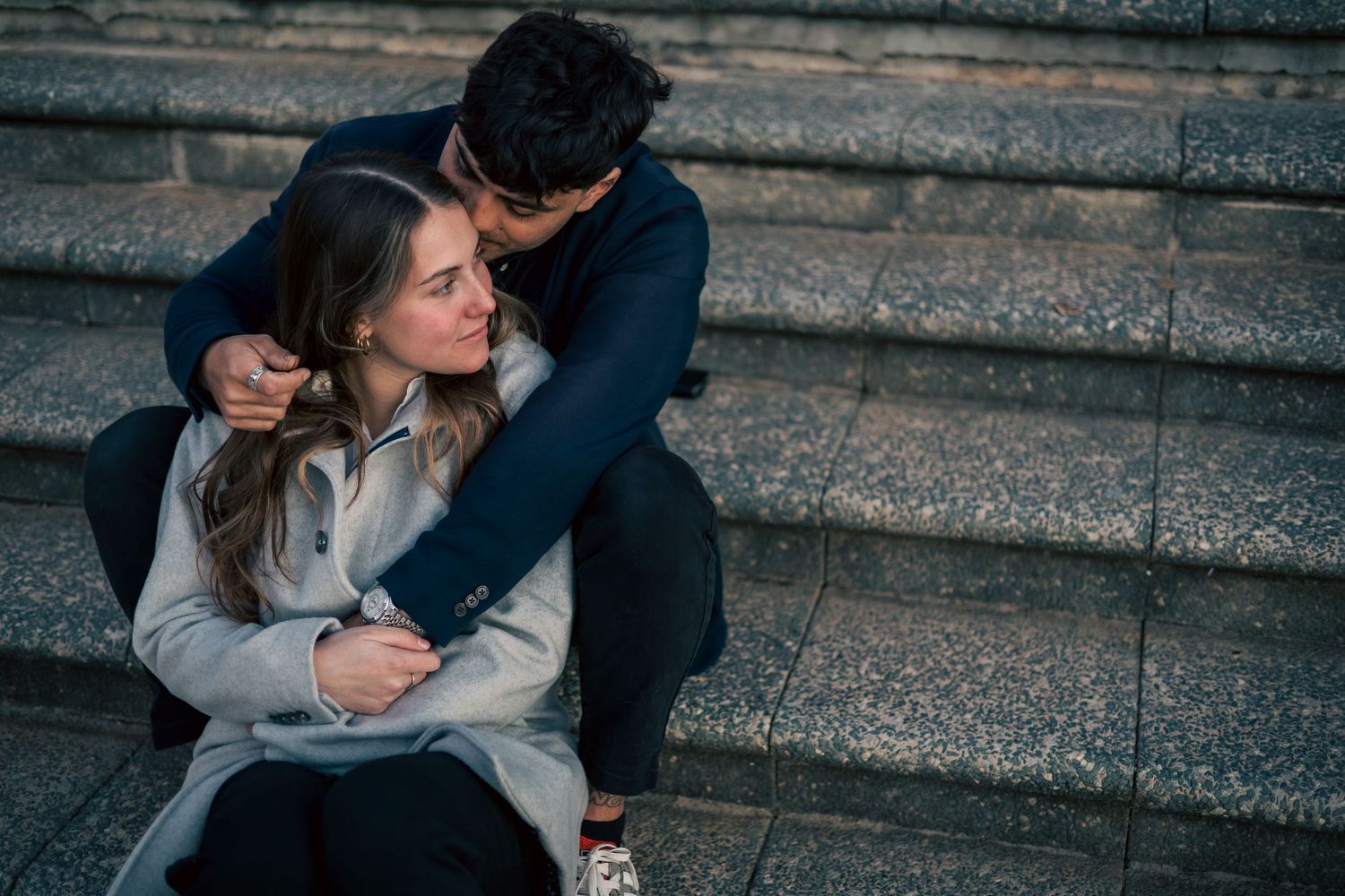 A romantic moment shared on concrete steps during late afternoon light.