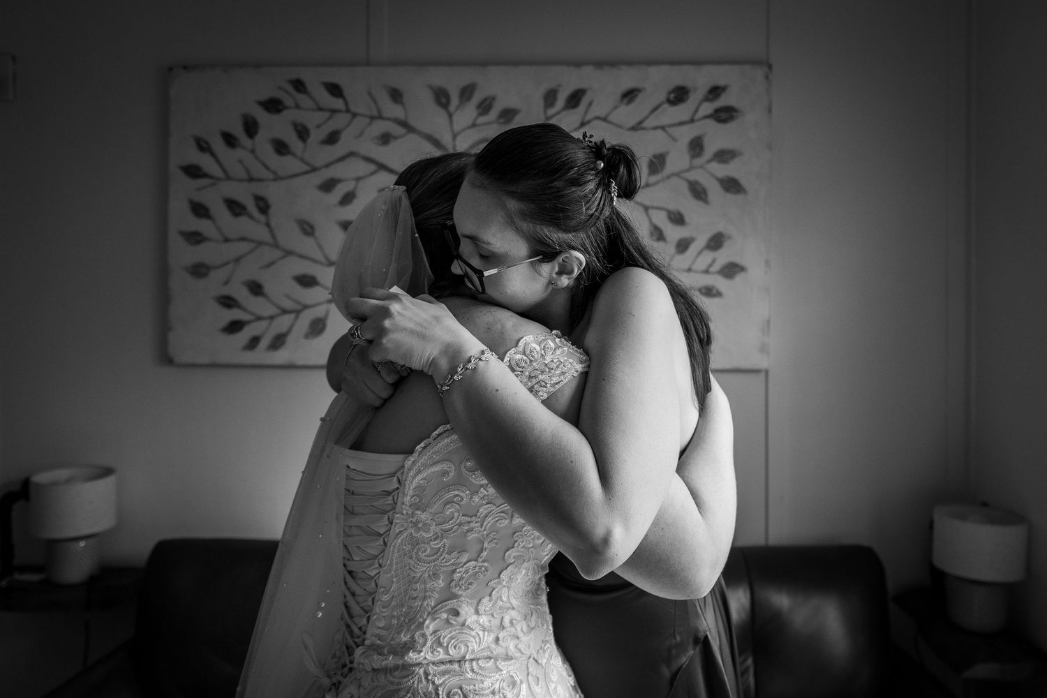 Two women sharing an emotional hug in black and white, one wearing a wedding dress.