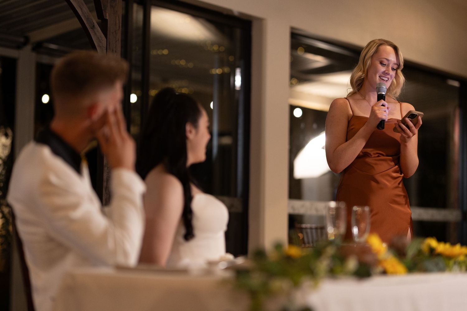 Indoor wedding reception with guests mingling and celebrating at tables.