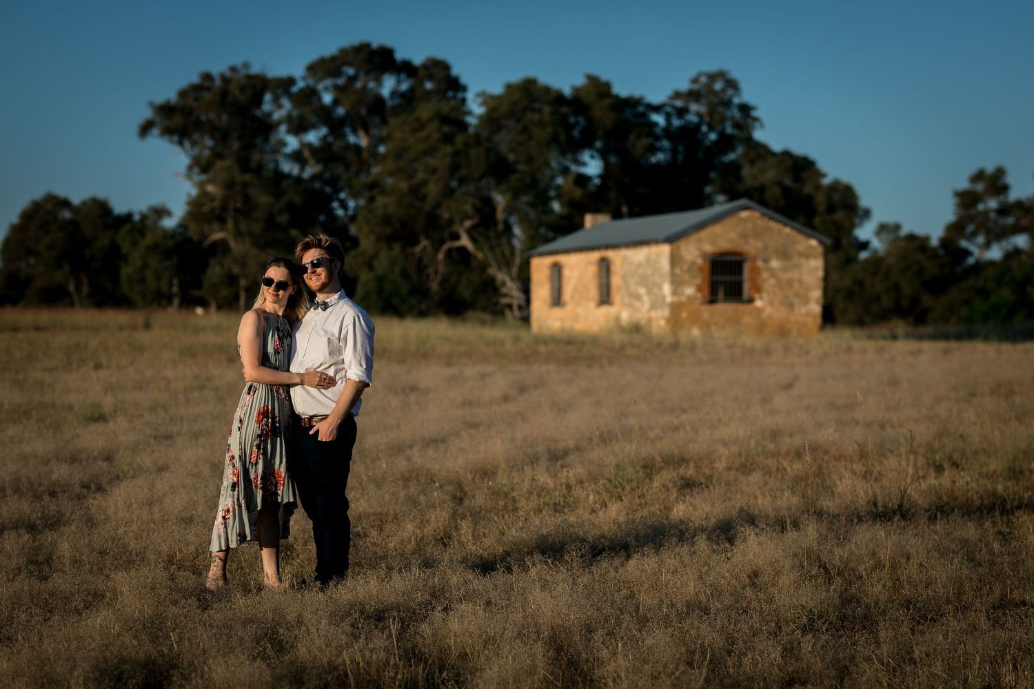 A rustic stone building sits in the distance of a rolling countryside landscape.