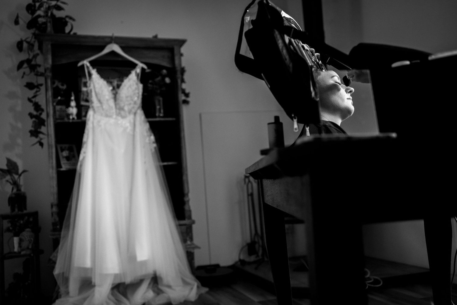 A black and white photo of a wedding dress hanging in preparation for the big day.