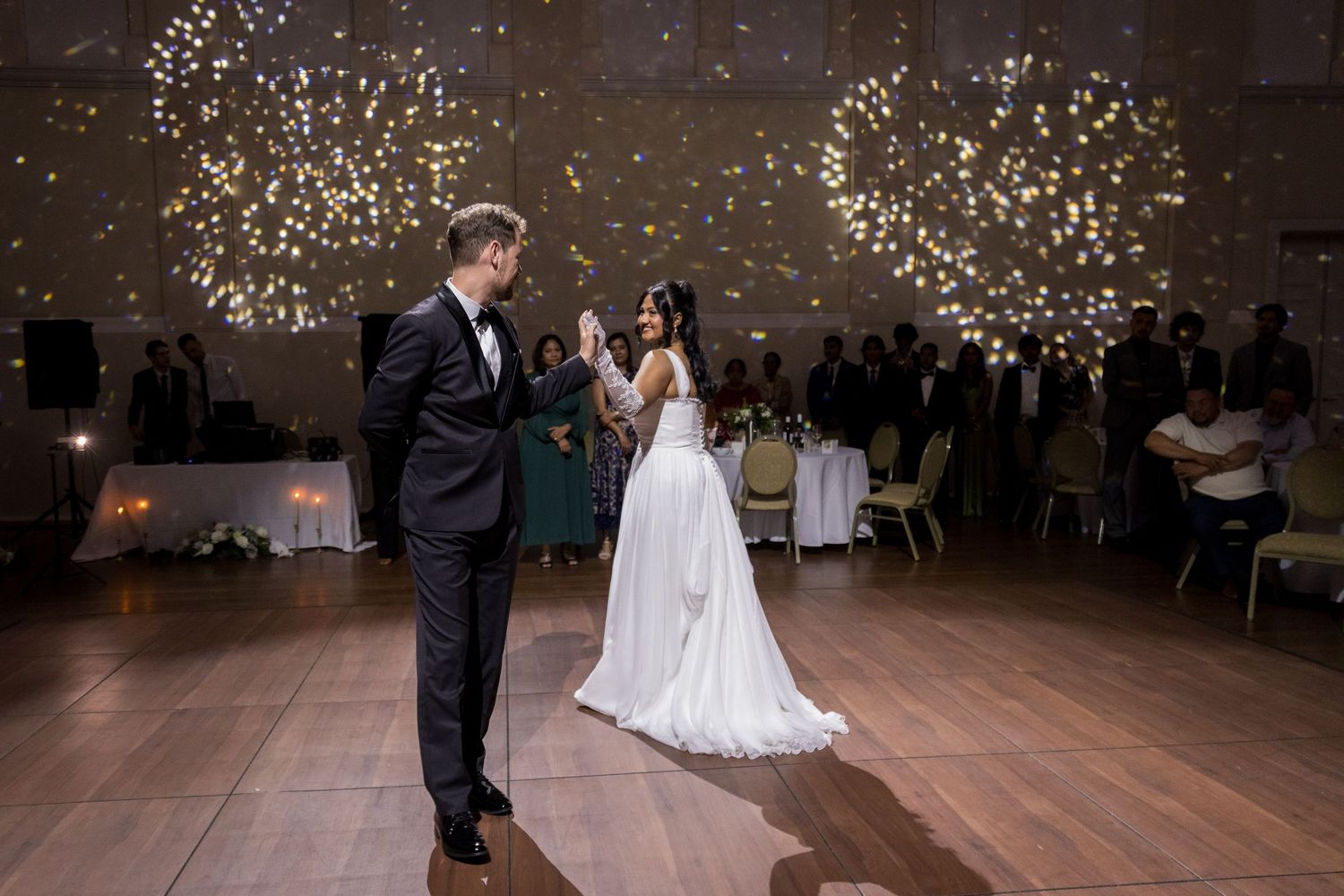 Bride and groom share their first dance under sparkling star-like lights at an elegant wedding reception at Montgomery Hall