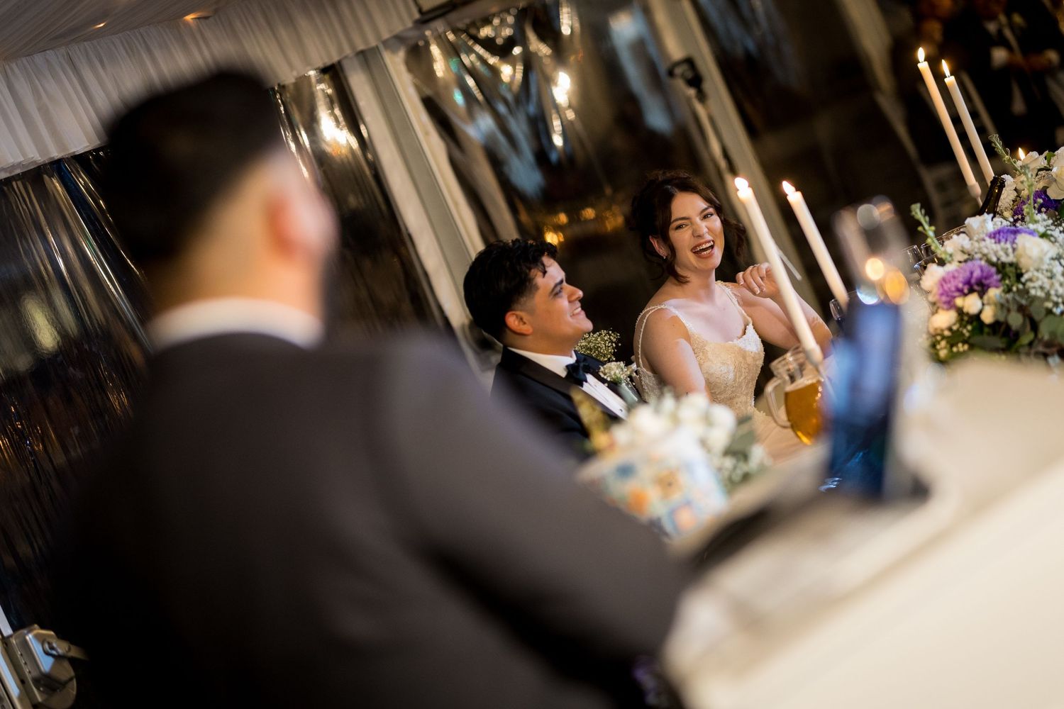 Candid moments captured during an indoor wedding reception with ambient lighting.