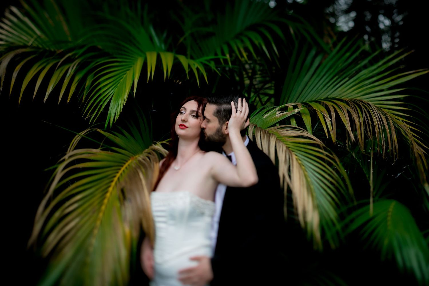 Dramatic portrait against dark tropical foliage with palm fronds.