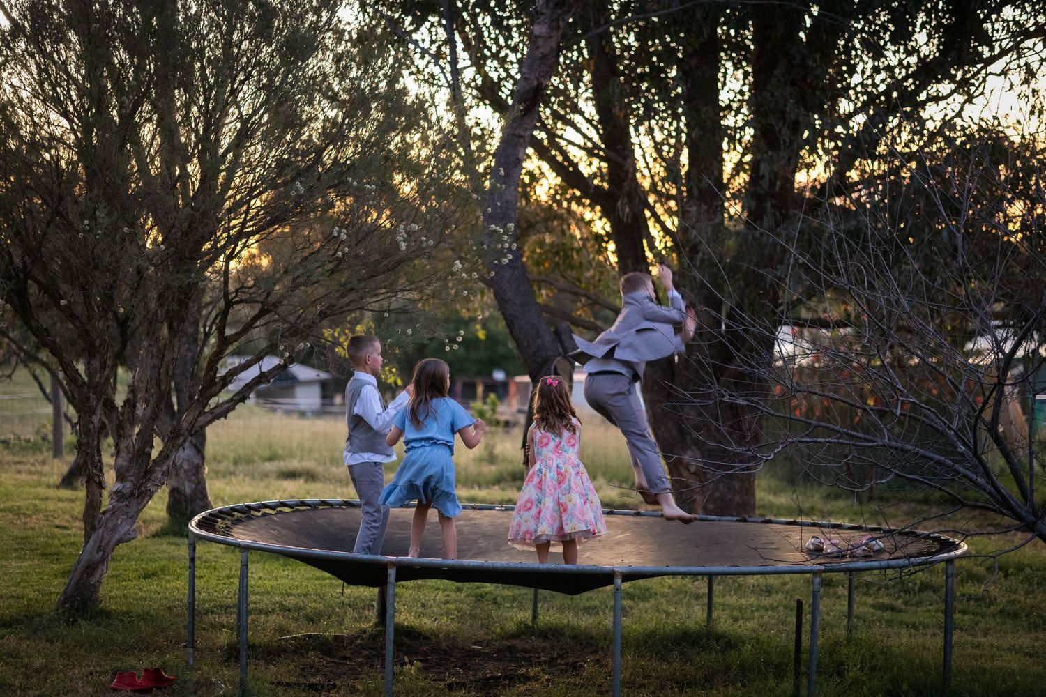 Children playing on swings at sunset during an outdoor wedding celebration.