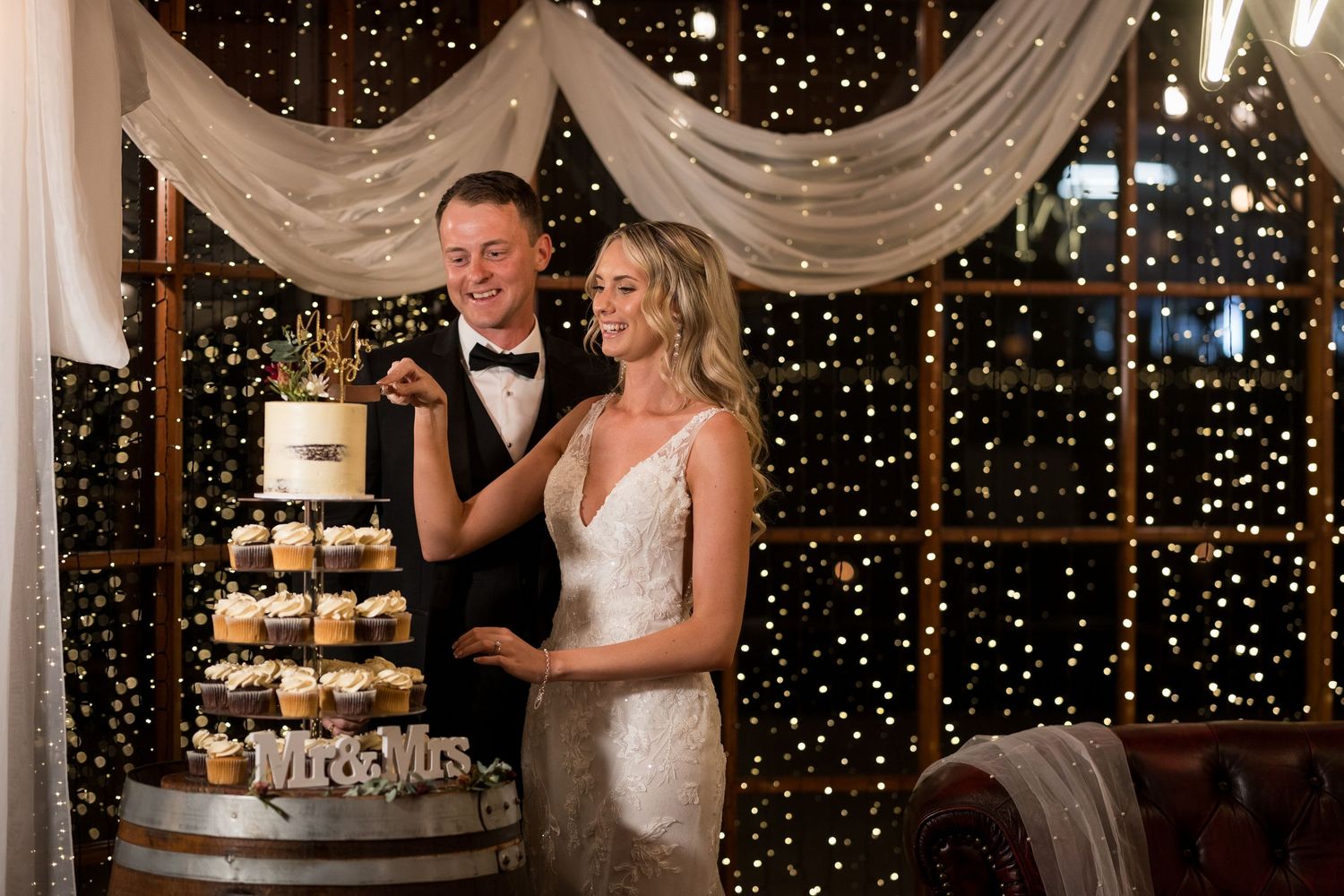 Elegant barn wedding reception with fairy lights and white fabric decorations.