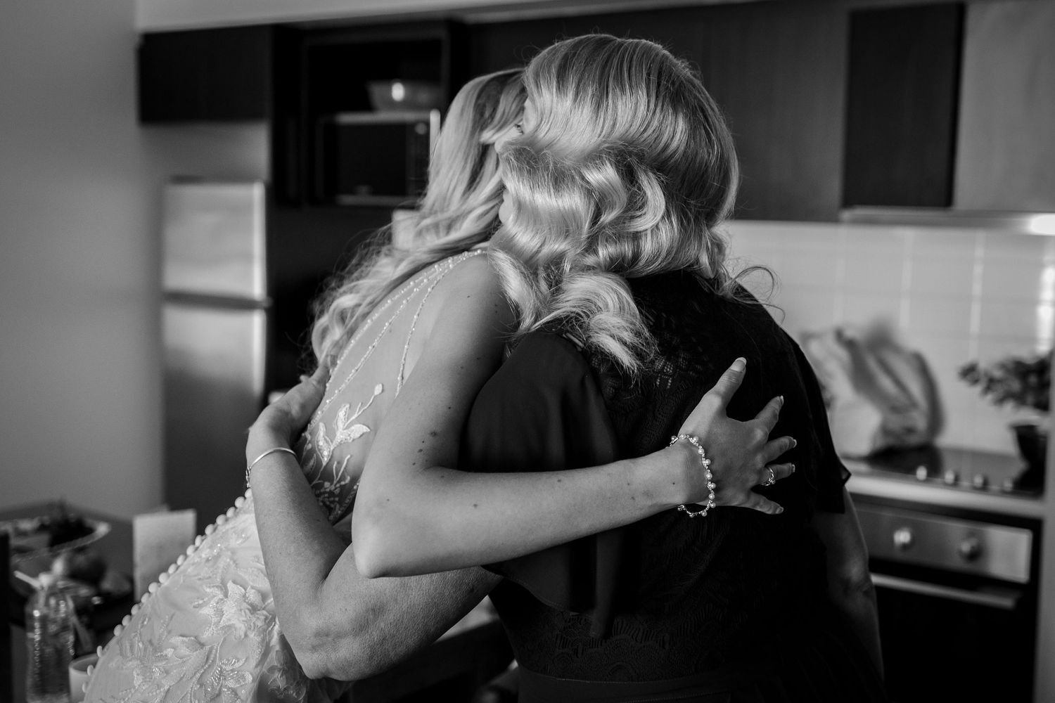 Emotional black and white wedding moments captured in candid hugs and embraces.