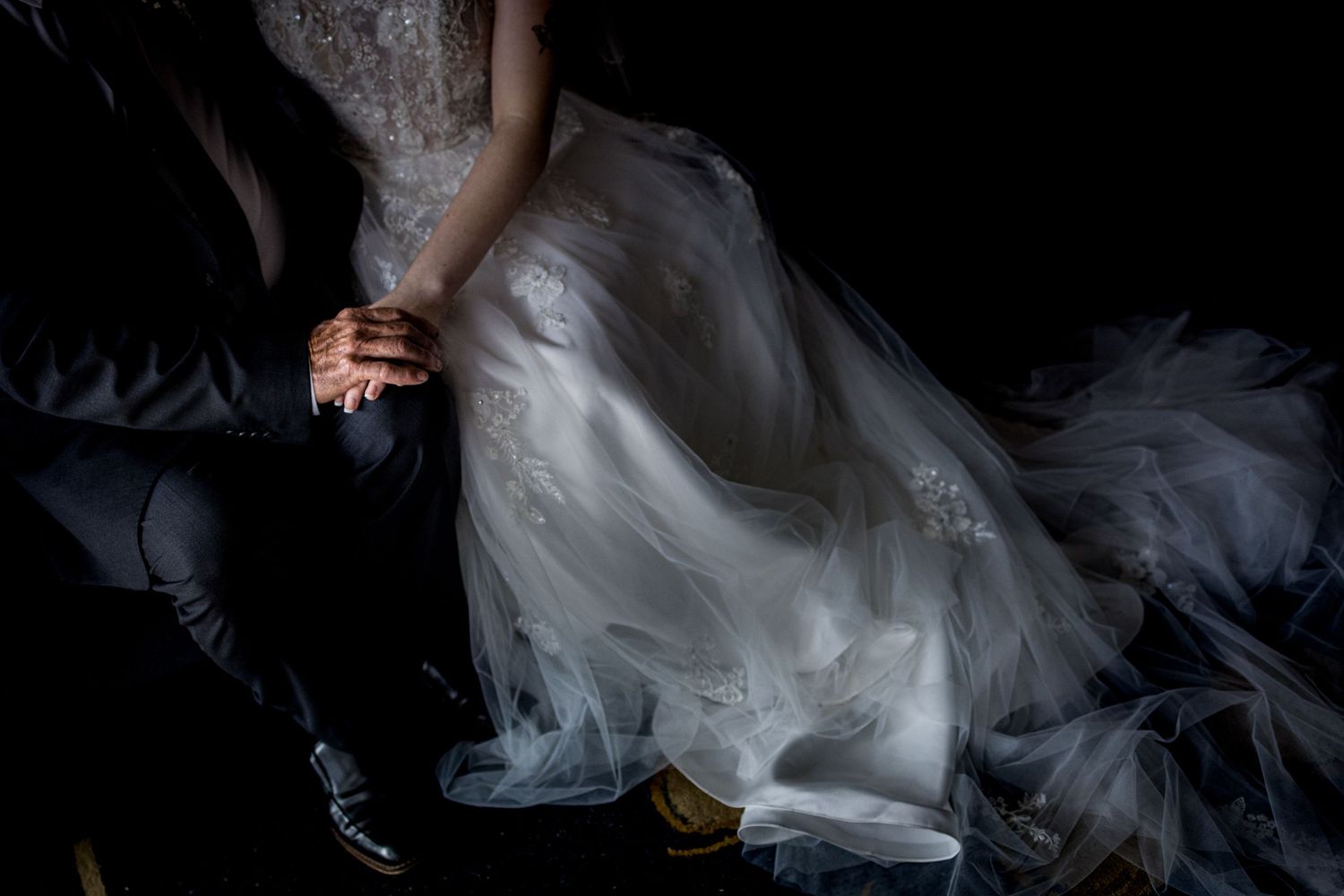 Close-up detail of flowing wedding dress fabric in dramatic lighting.