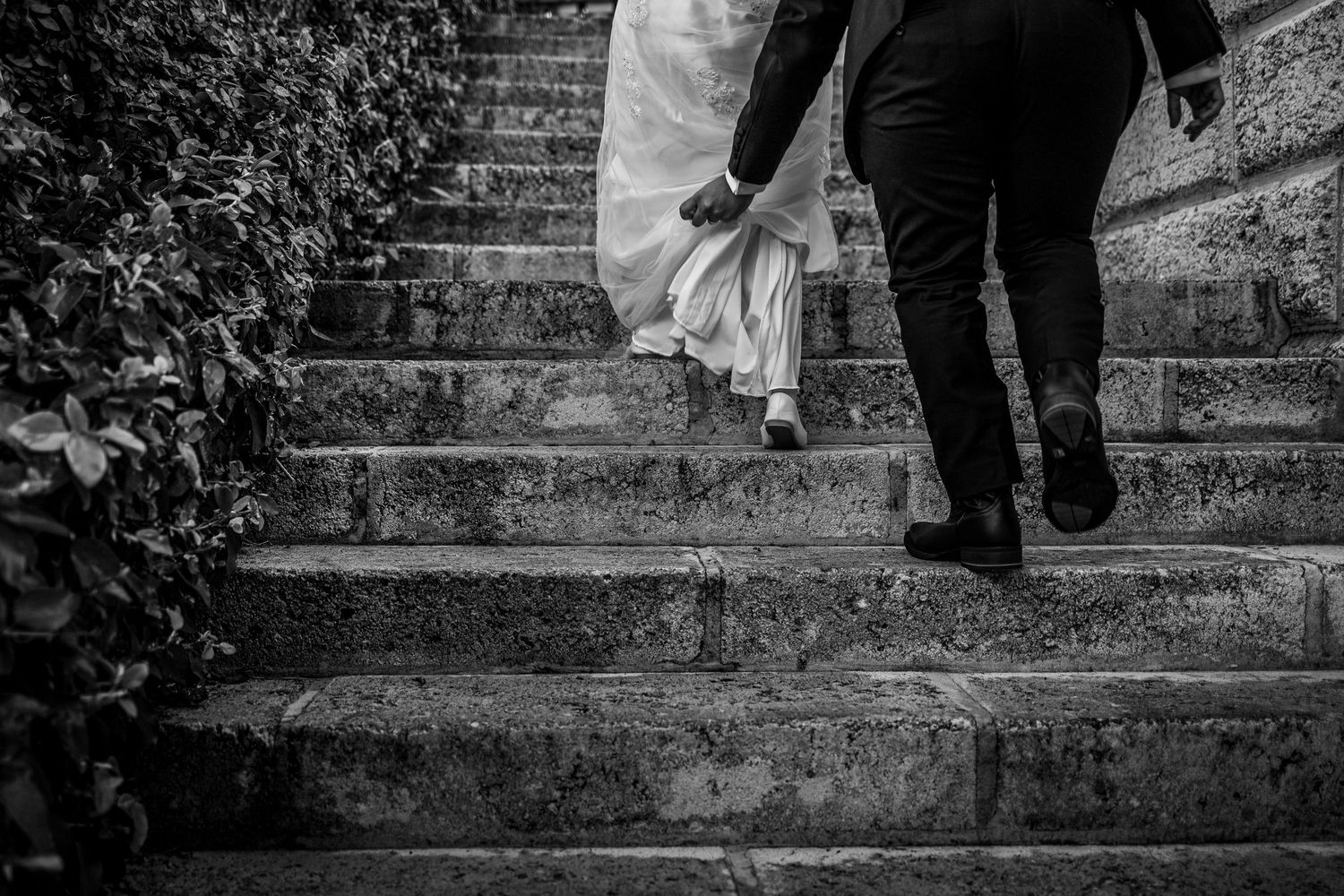 Black and white photo of wedding couple ascending historic stone steps.