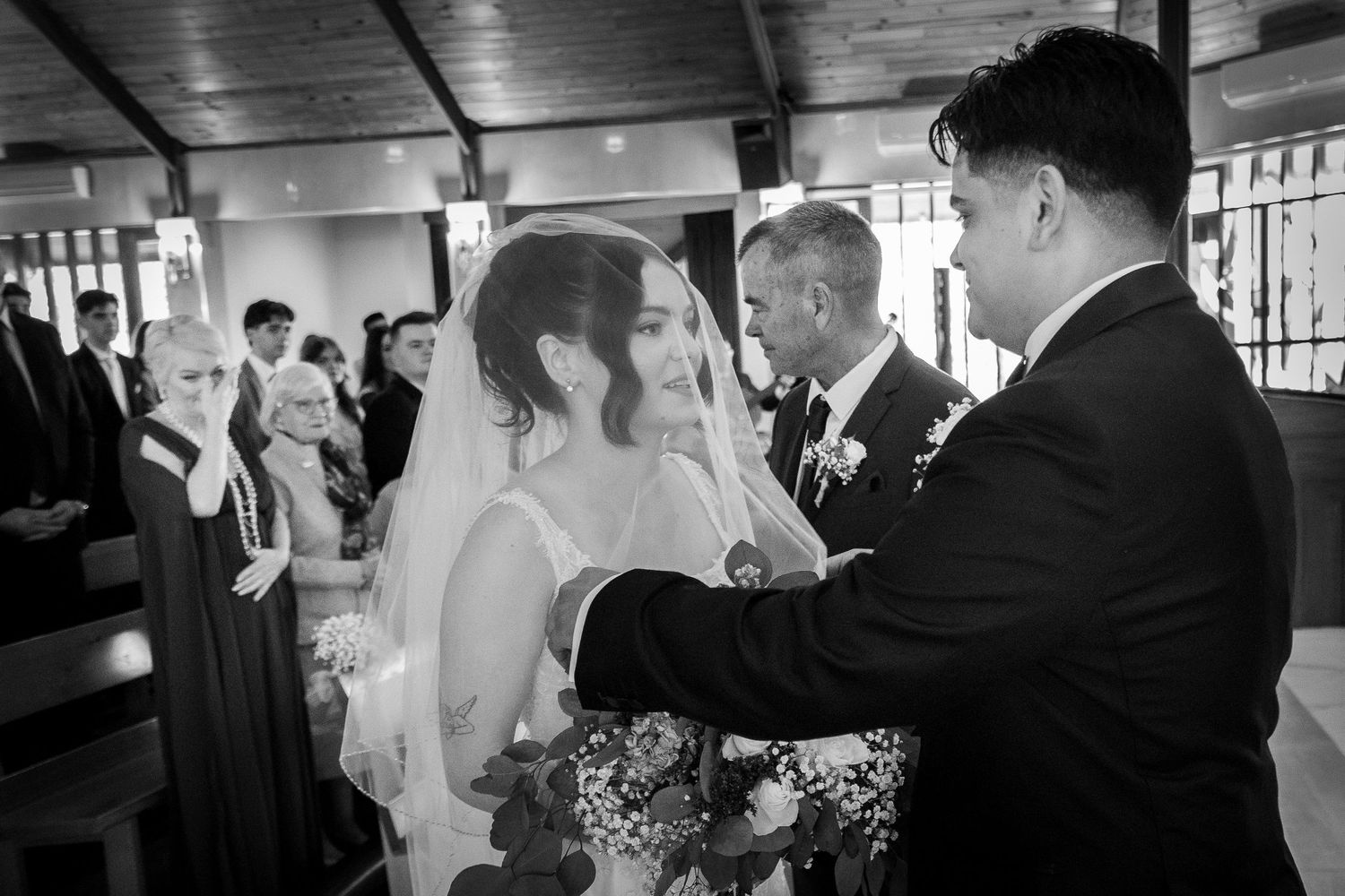 Black and white wedding ceremony scene in a traditional church setting.