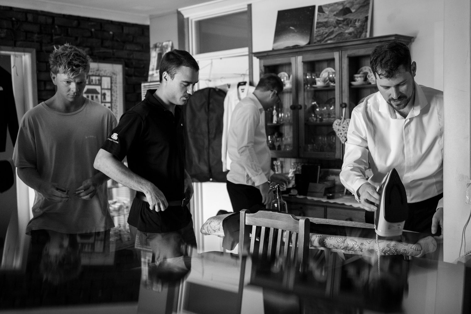 Black and white photo of three young men working together in a stylish home interior with vintage furniture.