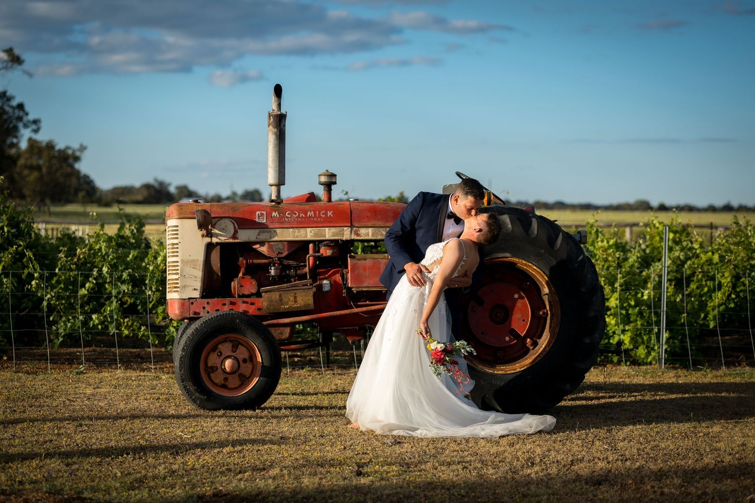 Artistic panoramic shots of newlyweds with vintage red tractor in rustic farm setting.