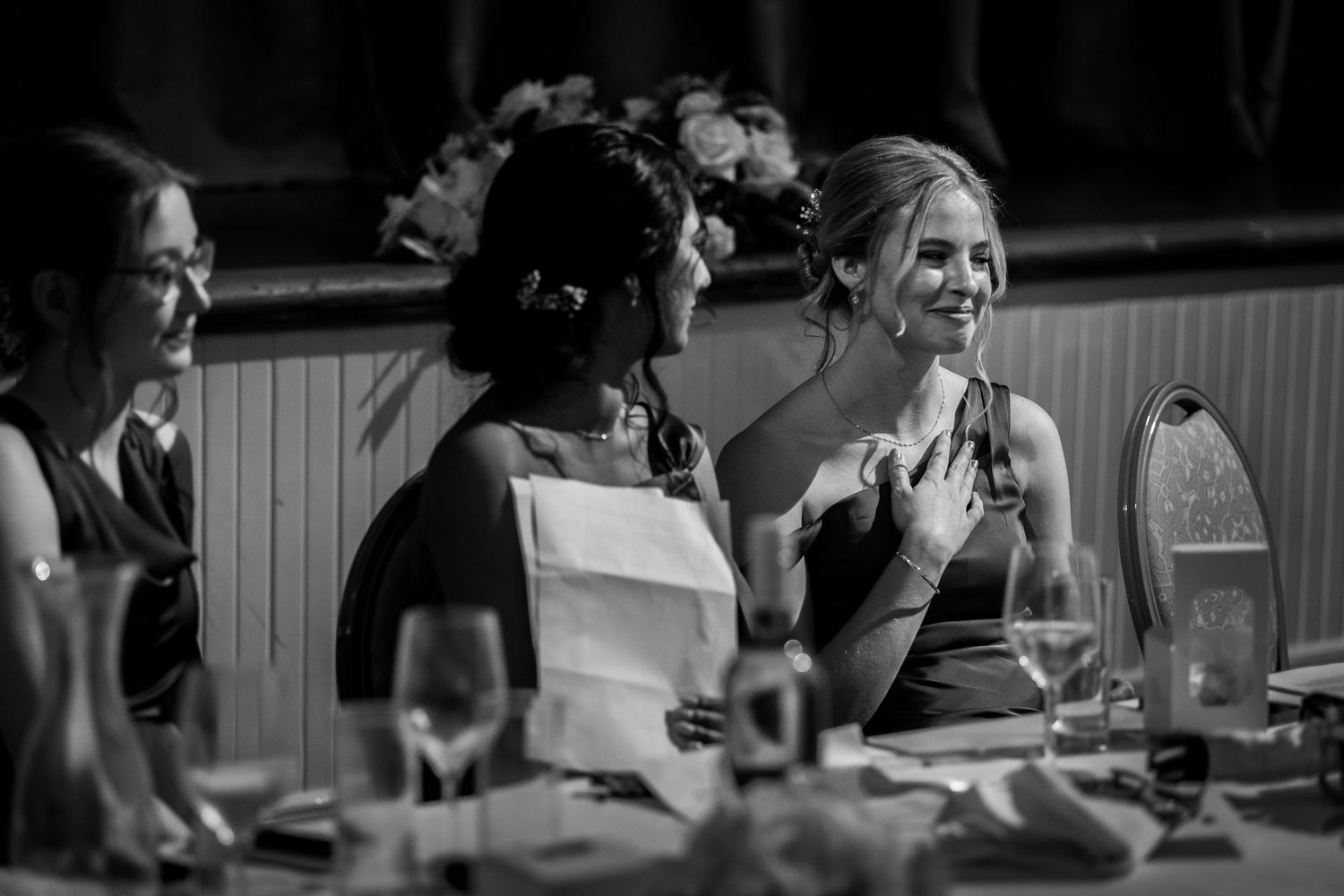 Black and white photo of women laughing at a wedding reception dinner table with elegant glassware at Montgomery Hall