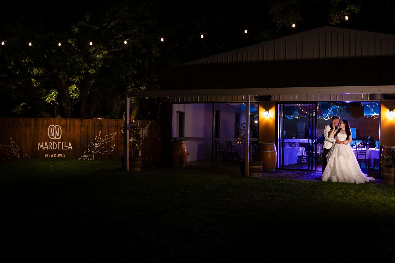 Nighttime exterior view of a wedding venue with illuminated signage and decorative lighting.