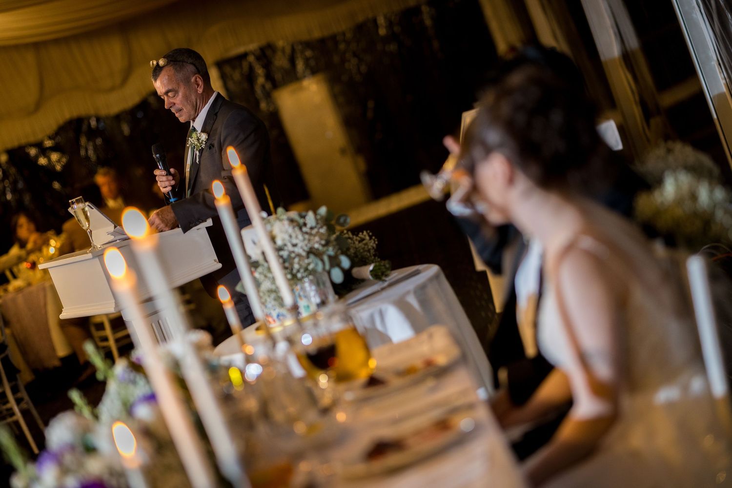 Elegant wedding reception dinner setup with candlelit tables and formal place settings.
