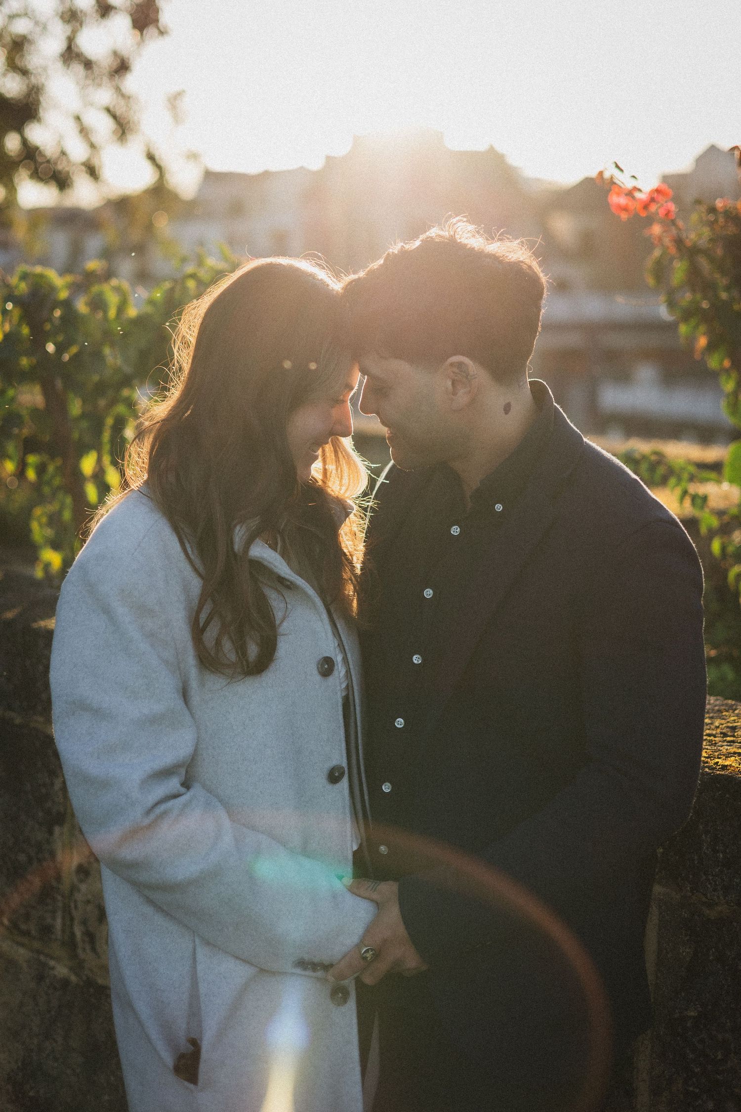A romantic sunset moment captured between two people in a garden with golden sunlight streaming through.
