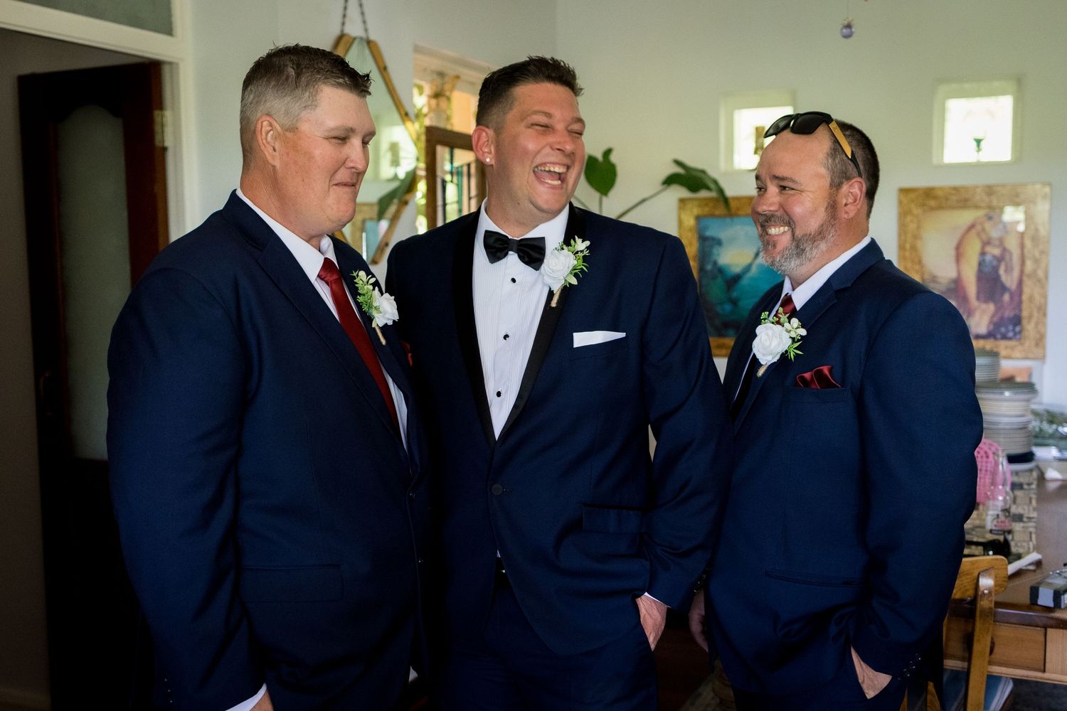 Groomsmen sharing a laugh while wearing matching navy suits.