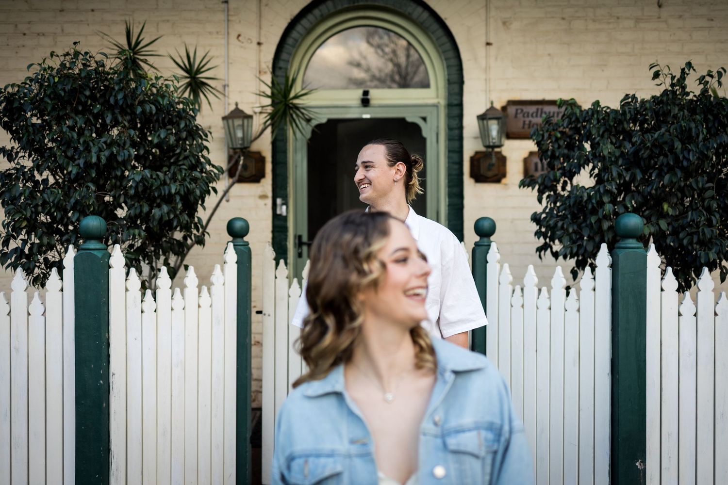 Couple posing outside a charming heritage home with white picket fence and lush green plants. at Guildford, Perth